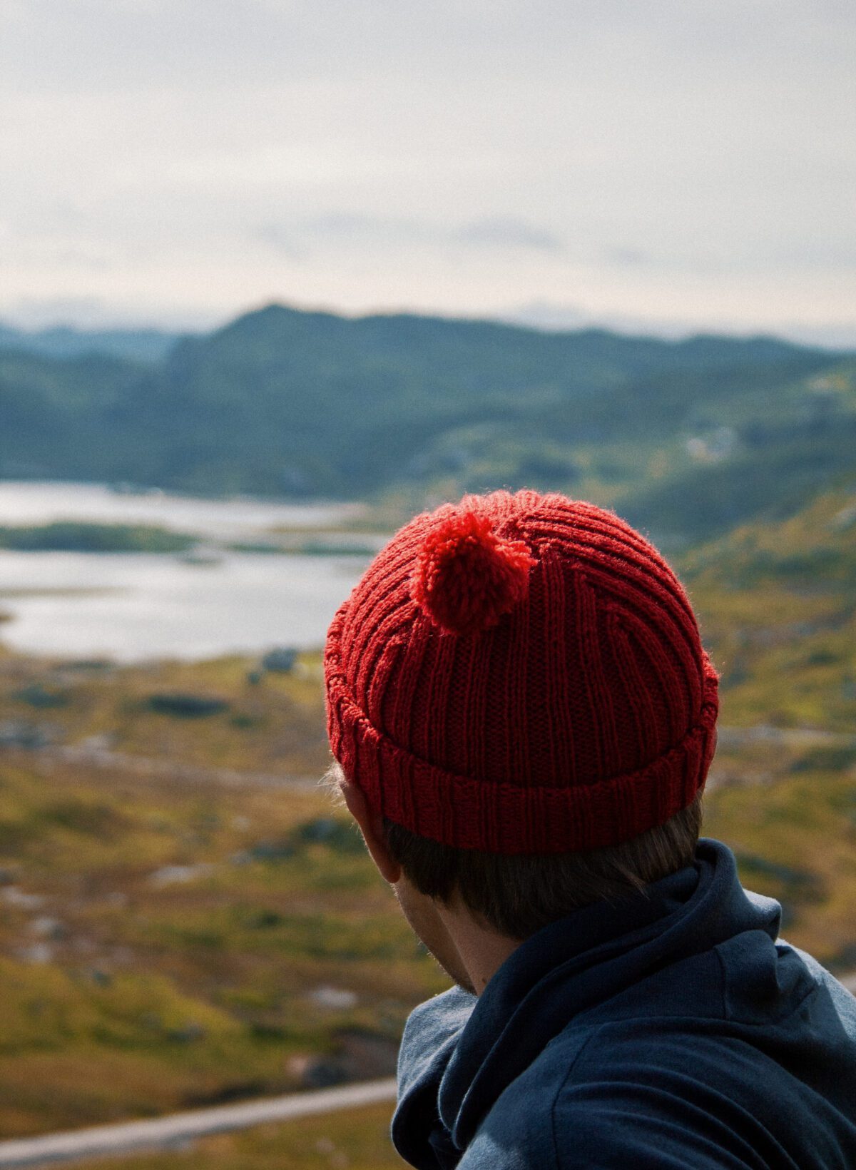 Hand knit beanie with pom-pom in the mountains.
