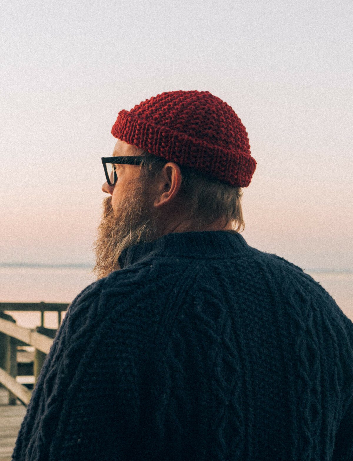 Red hand knit chunky wool beanie work by a man by the lake