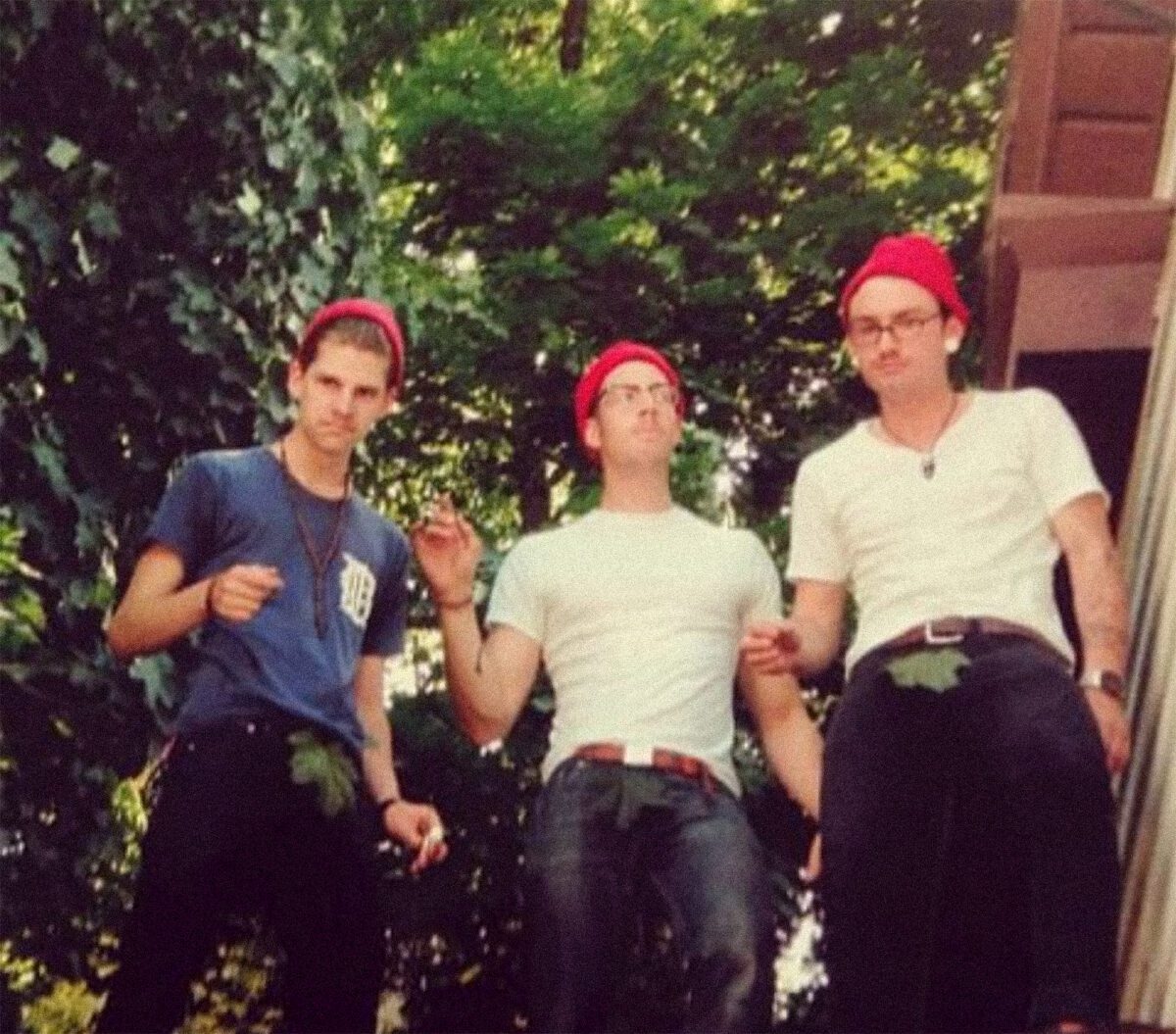 Three men wearing red beanies